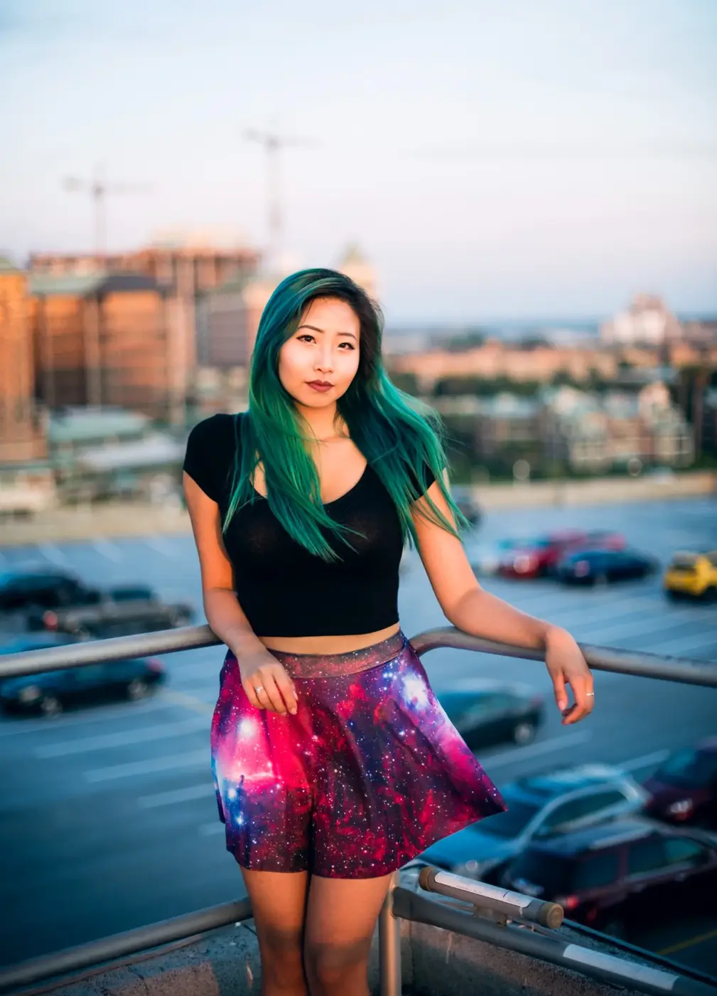 Rooftop portrait of a woman with teal hair and a colorful skirt