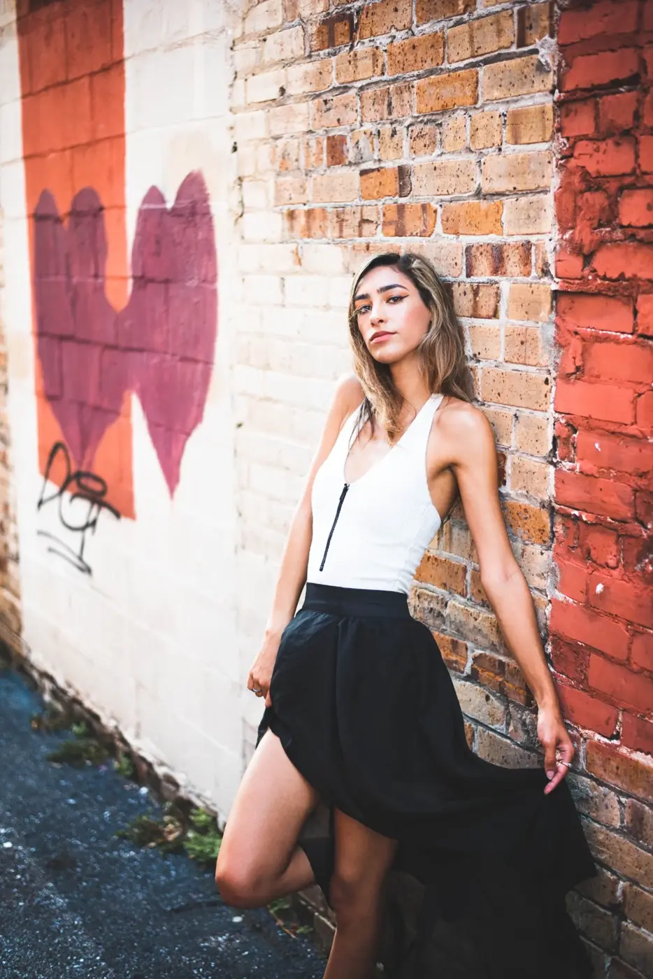Portrait of a woman beside a painted brick wall
