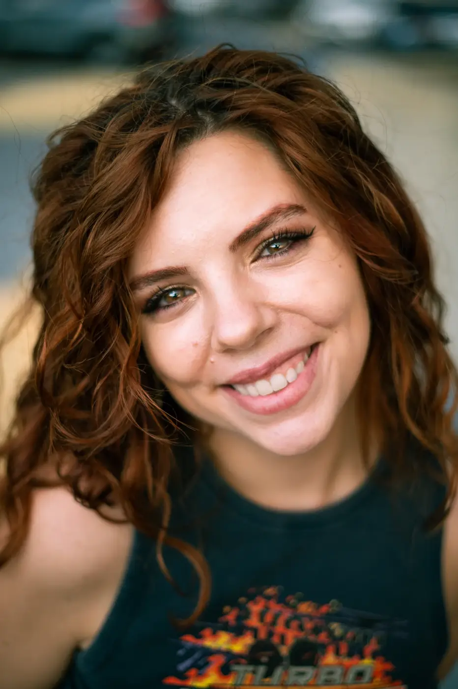 Close-up portrait of a smiling woman with curly auburn hair