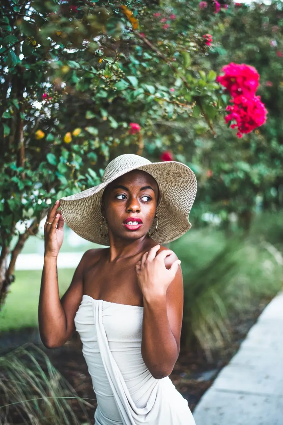 Portrait of a woman wearing a sunhat beneath flowering trees